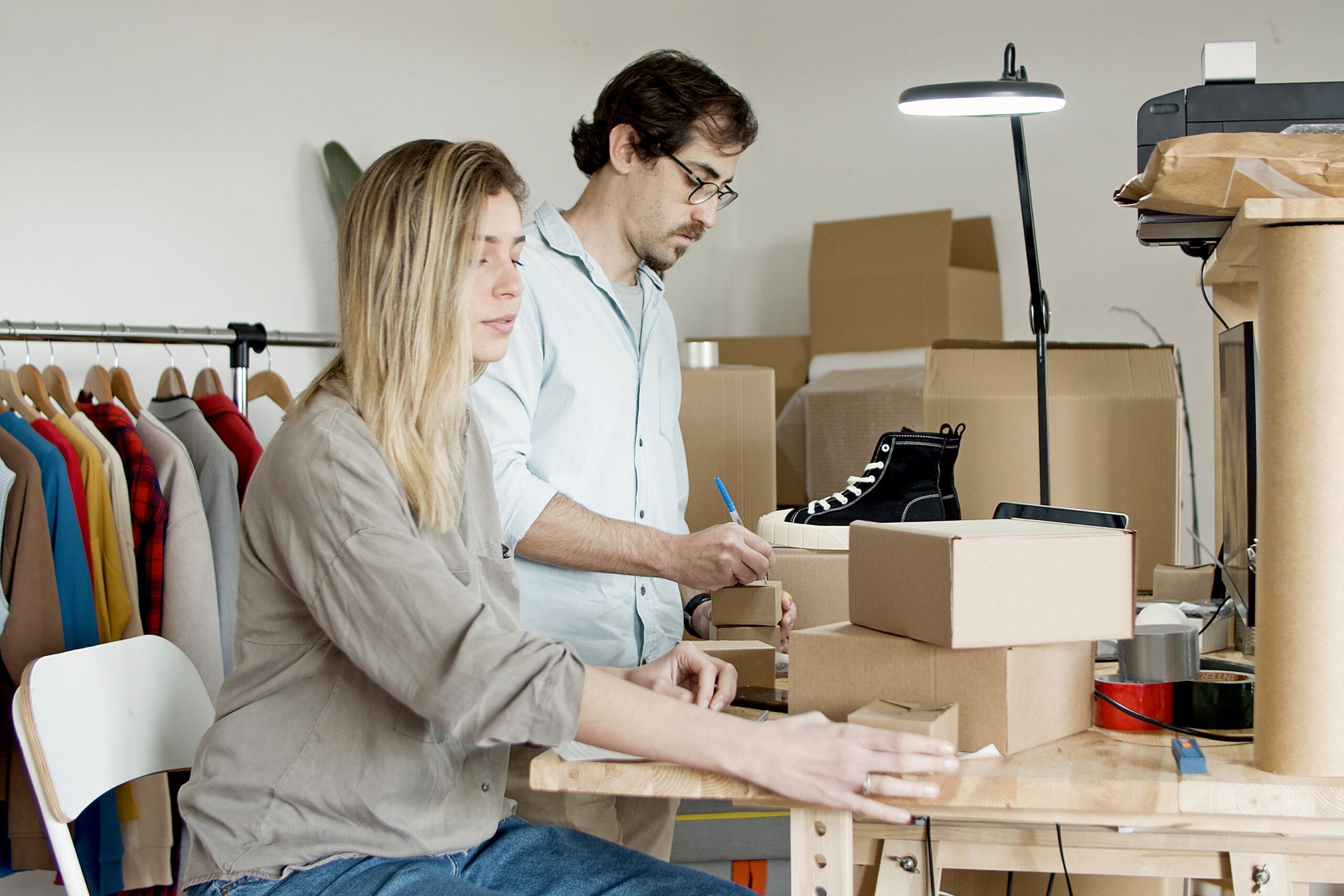Small business owners packaging products for shipment, representing an Etsy seller managing orders and fees