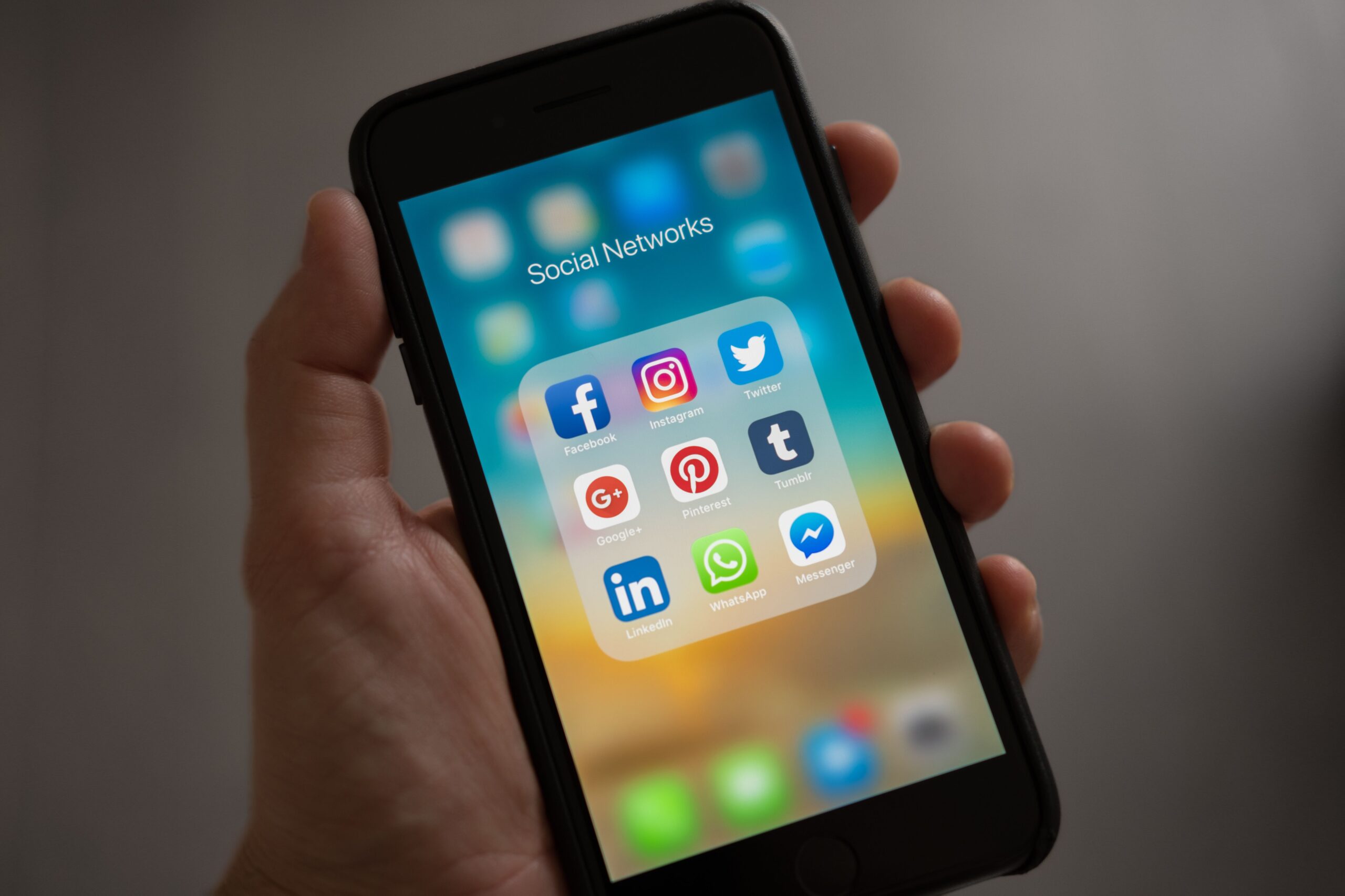 A person holding a smartphone showing social media apps, representing traffic sources used for CPA offers