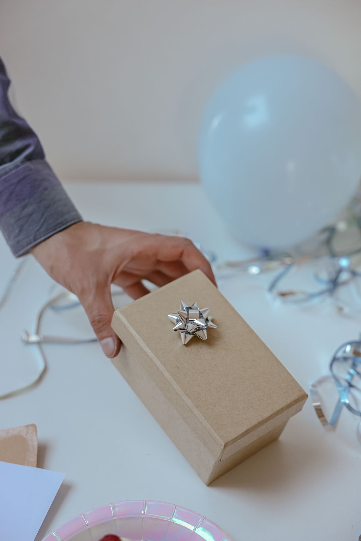 Hand reaching for a small wrapped gift box with a balloon in the background, representing fake giveaway and contest scams