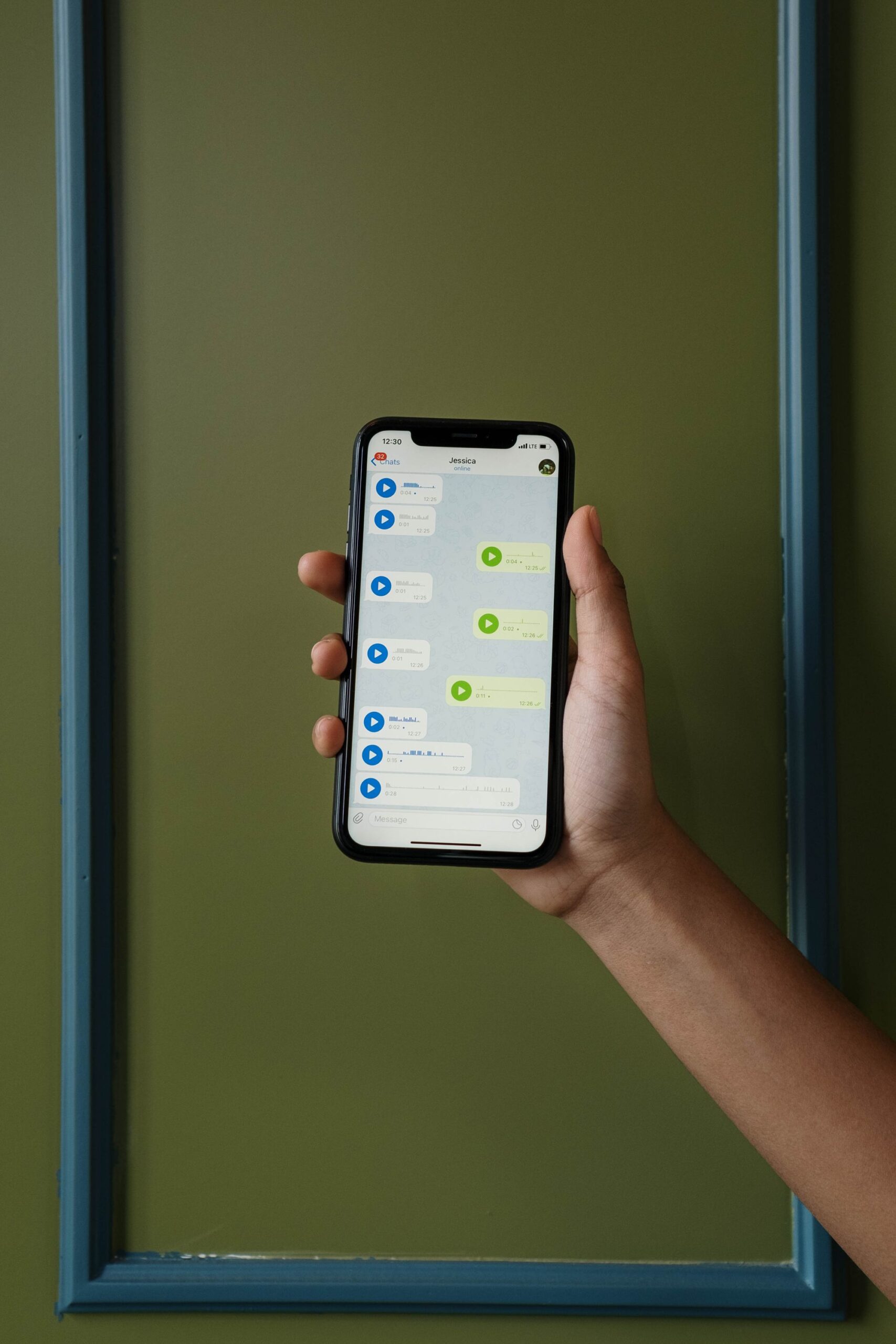 Illustrative close-up of a hand holding a smartphone displaying a chat conversation, representing a fake remote job offer sent via message