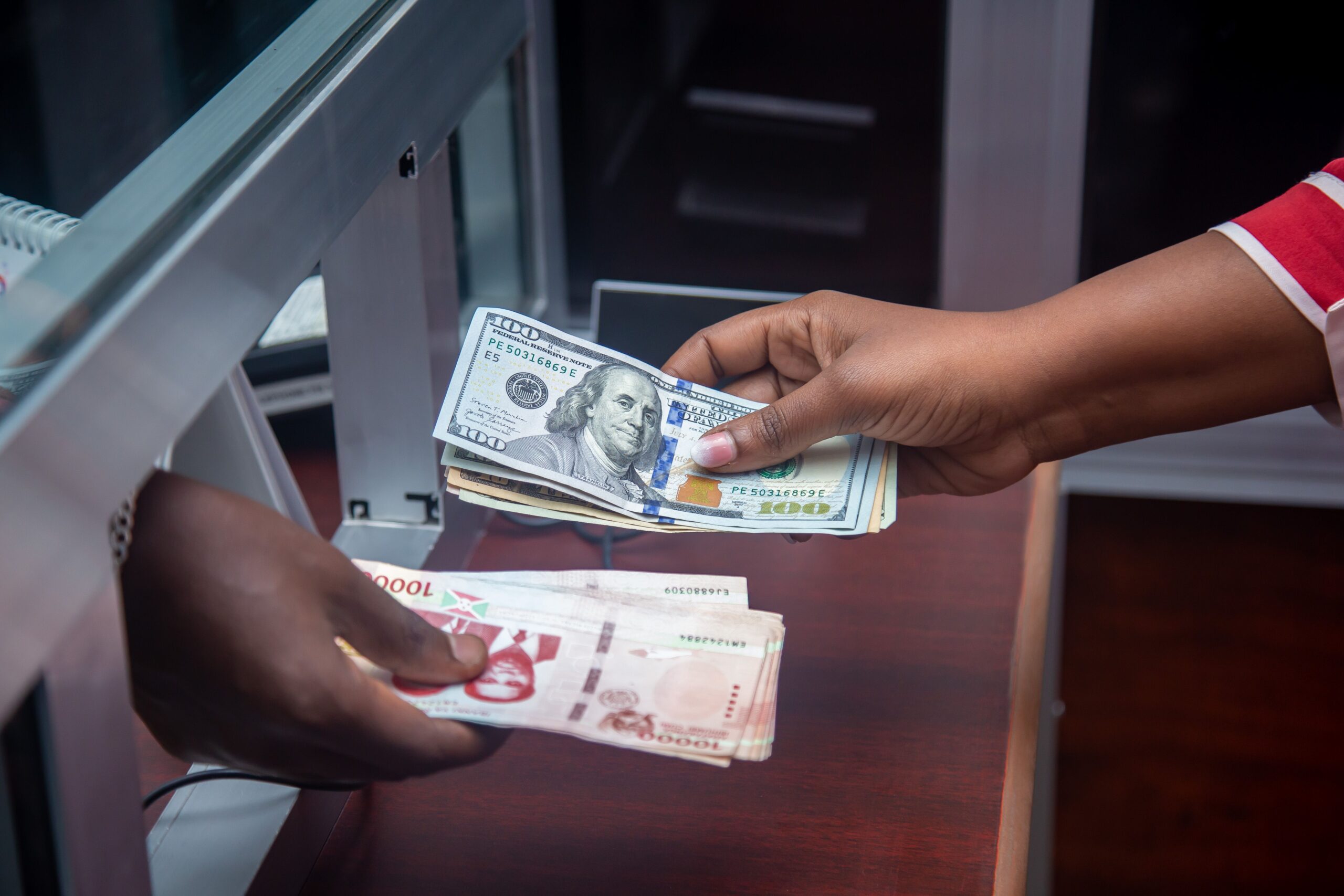 Close-up of two hands exchanging cash bills at a counter, representing a community savings pool contribution