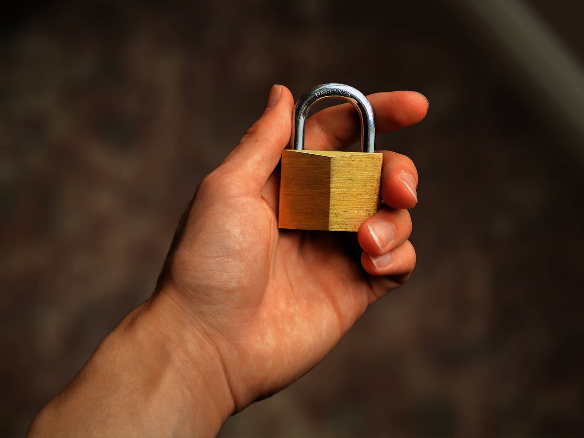 Hand holding a small padlock, representing social media account takeover and security